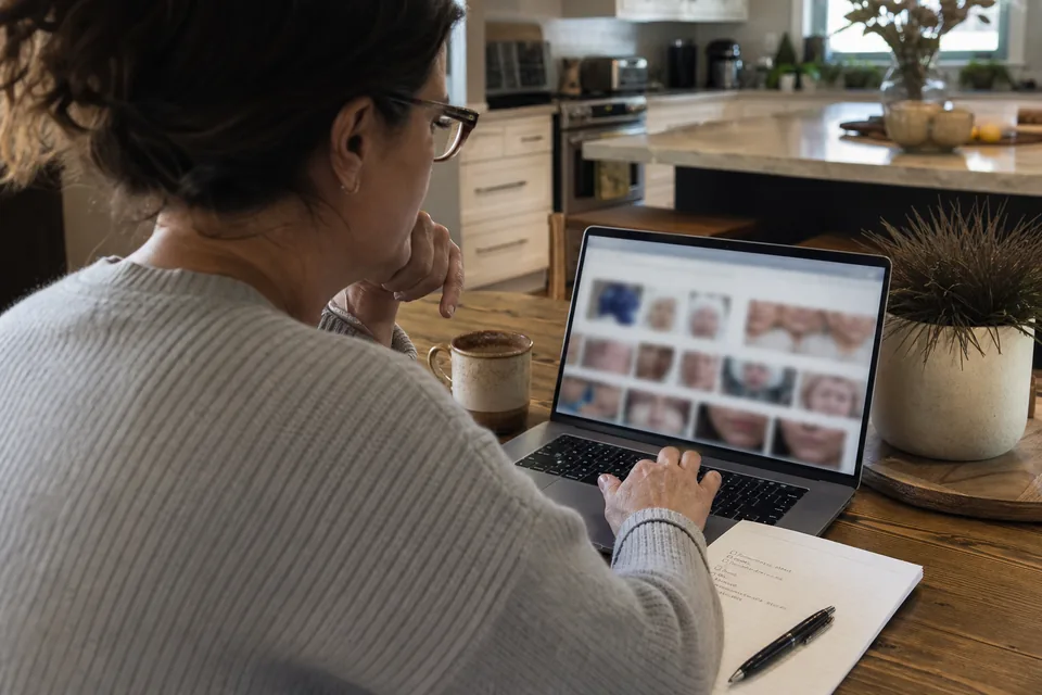 Woman researching cosmetic surgery consultations on a laptop at her kitchen table